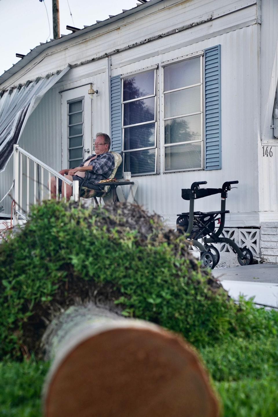 Monty Covert sits on the porch of his mobile home in Englewood, Florida, surveying the damage to his neighborhood after Hurricane Ian on Friday, Sept. 30, 2022.