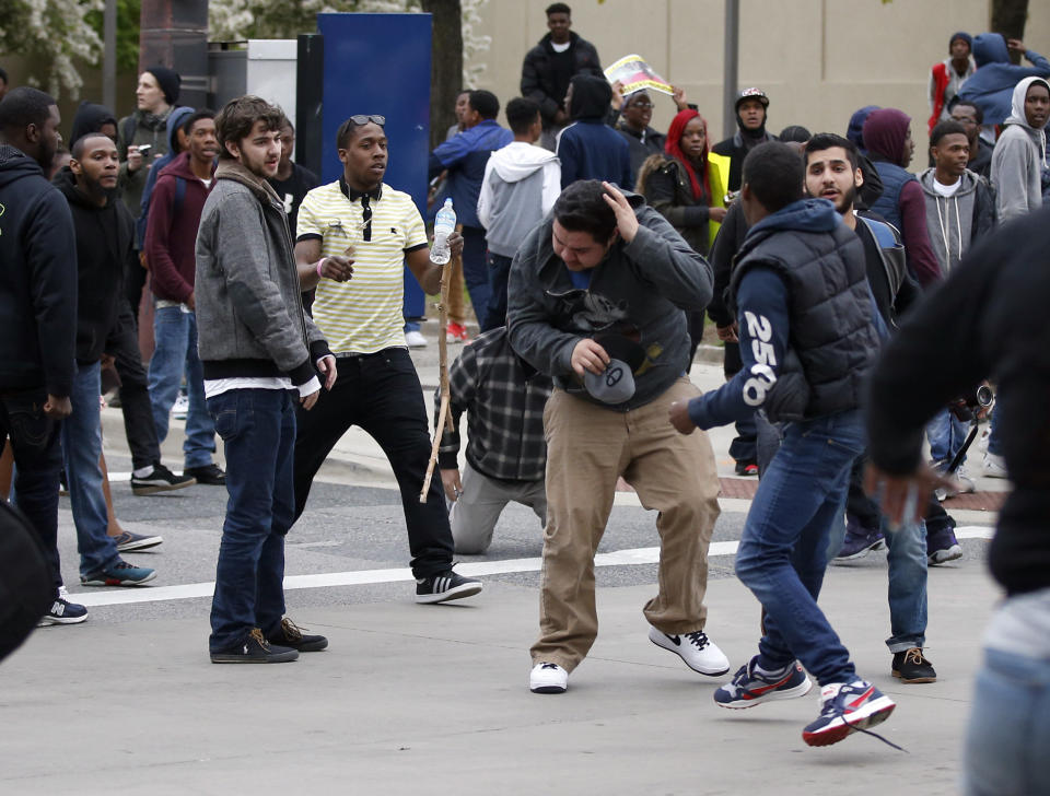 A man, center, shields himself after being struck after a march to City Hall for Freddie Gray, Saturday, April 25, 2015 in Baltimore. Gray died from spinal injuries about a week after he was arrested and transported in a police van. (AP Photo/Alex Brandon)