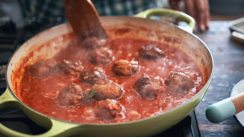 Meatballs cooking in a pot of red sauce