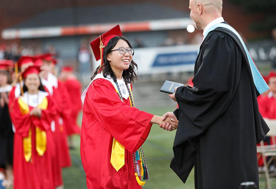 Valedictorian Dominique Dang receives her diploma from Principal Daniel Gilbert during North Quincy High School's commencement ceremony at Veterans Memorial Stadium on Tuesday, June 6, 2023.