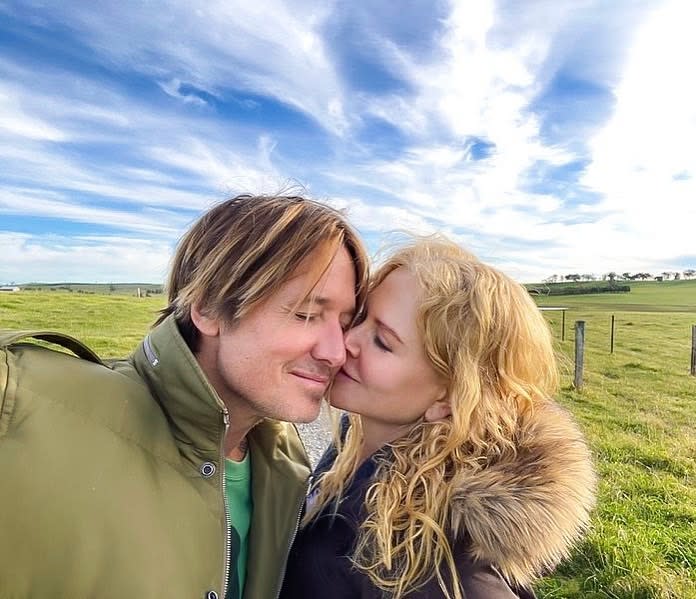 Nicole Kidman kisses husband Keith Urban on the cheek in a grassy field