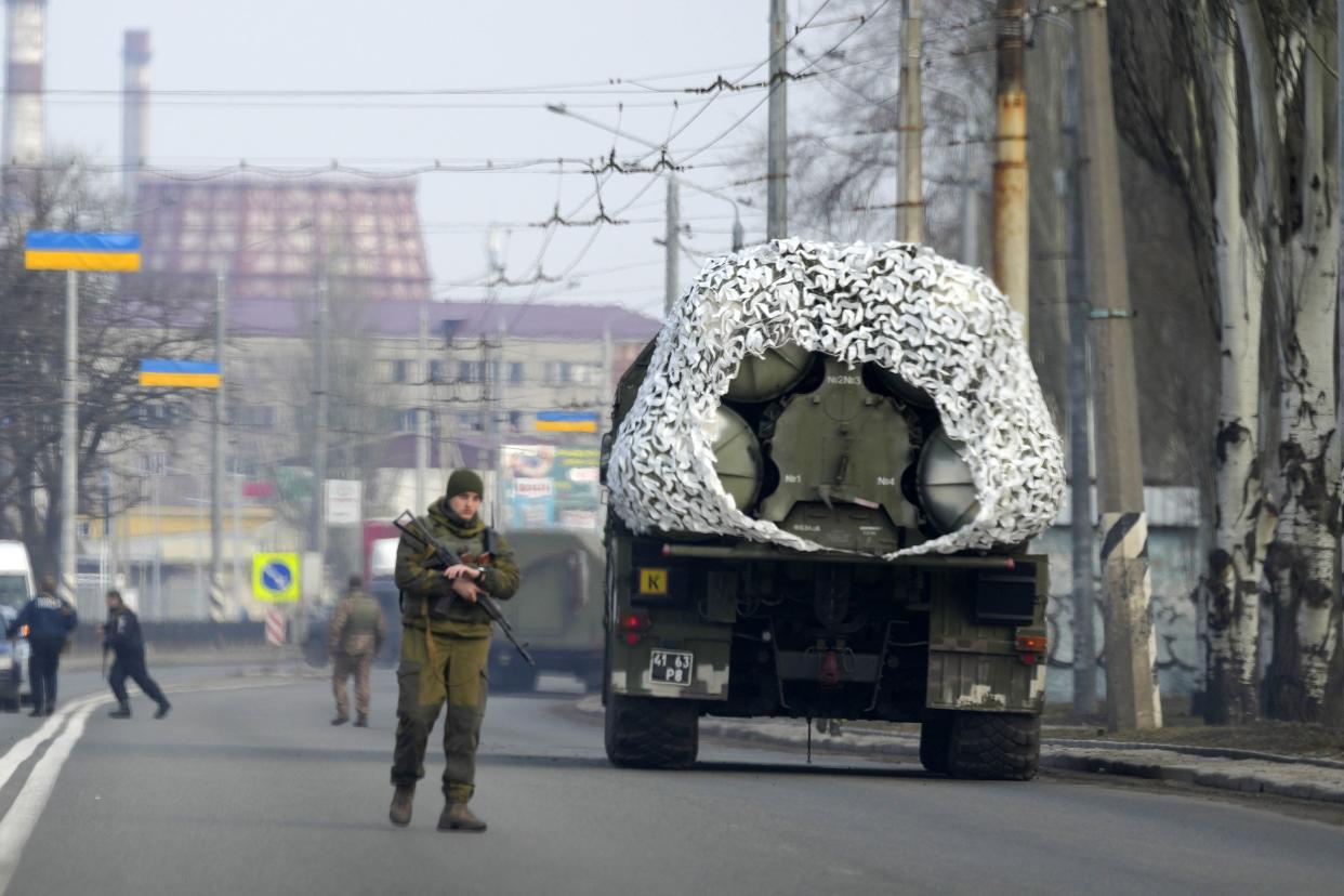 A Ukrainian soldier stands next to a military vehicle on a road in Kramatosrk, eastern Ukraine on Thursday, Feb. 24, 2022. Russian troops launched a wide-ranging attack on Ukraine on Thursday. President Vladimir Putin cast aside international condemnation and sanctions and warned other countries that any attempt to interfere would lead to "consequences you have never seen."