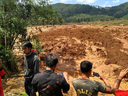 People take photos of a landslide in Brebes, Indonesia February 22, 2018, in this image obtained from social media. Aji Santoso/via REUTERS