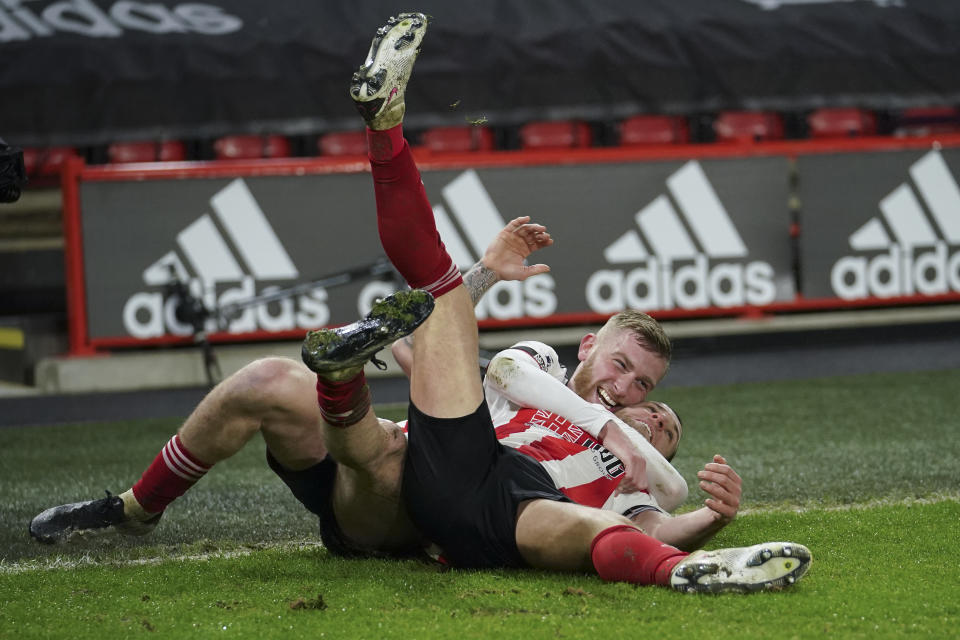 Sheffield United's Oliver McBurnie, rear, hugs teammate Billy Sharp who scored his side's second goal during the English Premier League soccer match between Sheffield United and West Bromwich Albion at Bramall Lane stadium in Sheffield, England, Tuesday, Feb. 2, 2021. (AP Photo/Dave Thompson, Pool)