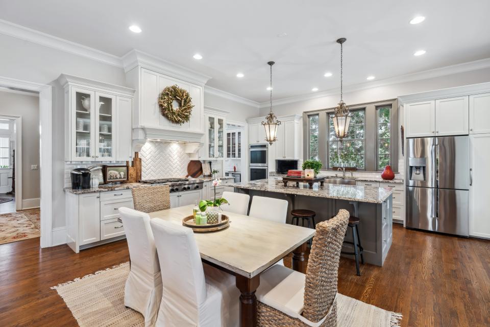 A white kitchen with a large island and table.