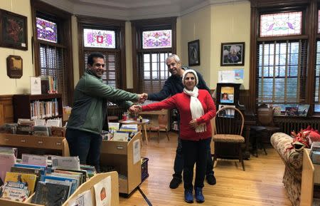 An Iranian family hold hands as they reunite at the Haskell Free Library and Opera House, which straddles the U.S.-Canada border in Stanstead, Quebec and in Derby Line, Vermont, U.S., November 3, 2018. Picture taken November 3, 2018. REUTERS/Yeganeh Torbati