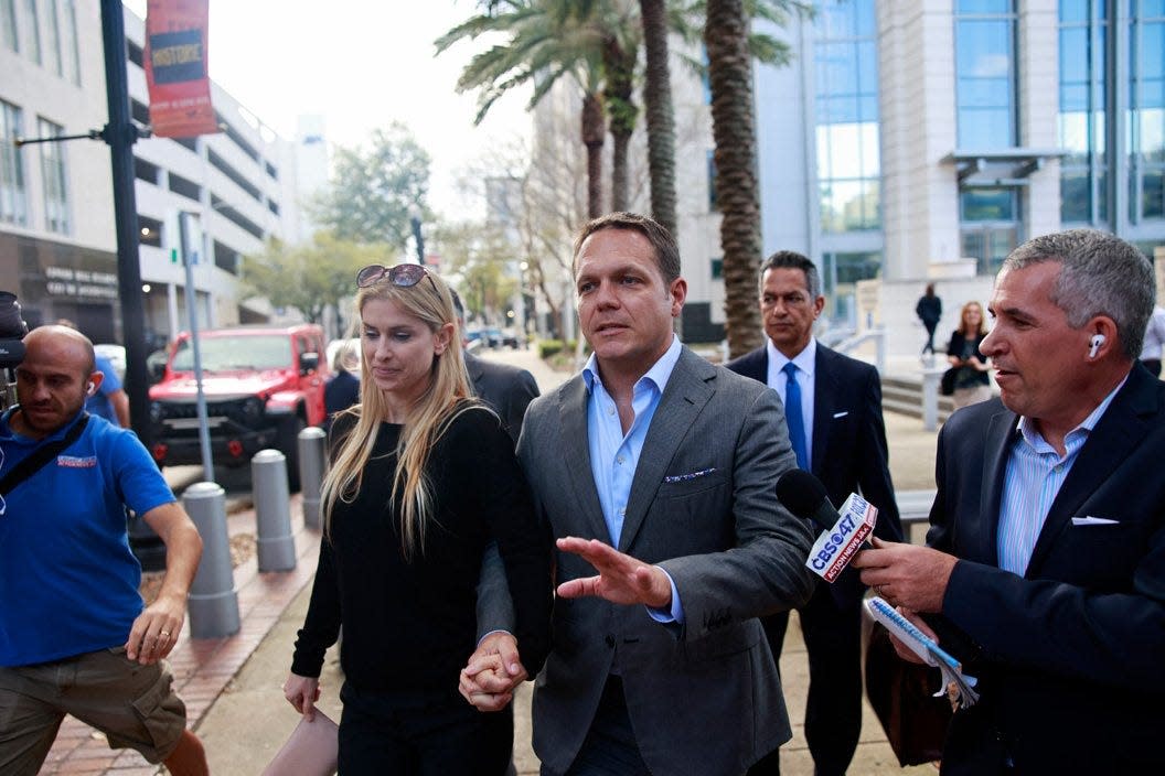 Ex-JEA CEO Aaron Zahn, center, leaves Federal Court with his wife, Mary Branan Ennis Zahn, left,  as Action JAX Reporter Ben Becker asks questions after a federal grand jury indictment hearing Tuesday, March 8, 2022 in Jacksonville. Aaron and former JEA Chief Financial Officer Ryan Wannemacher are accused of conspiracy and wire fraud. If convicted, they face up to 25 years in prison.