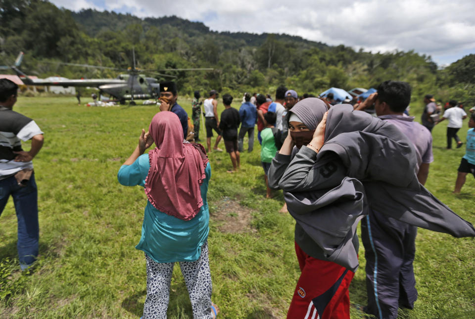 A Muslim woman covers her ears from the noise of an Indonesian Army helicopter dropping relief goods for earthquake survivors in Tolado village, Central Sulawesi, Indonesia, Sunday, Oct. 7, 2018. A 7.5 magnitude earthquake rocked Central Sulawesi province on Sept. 28, triggering a tsunami and mud slides that killed a large number of people and displaced tens of thousands others. (AP Photo/Dita Alangkara)