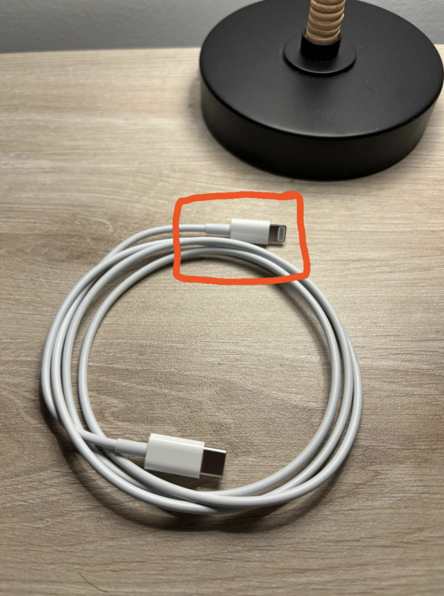 USB-C cable on a wooden desk, partially coiled, with a lamp base in the background