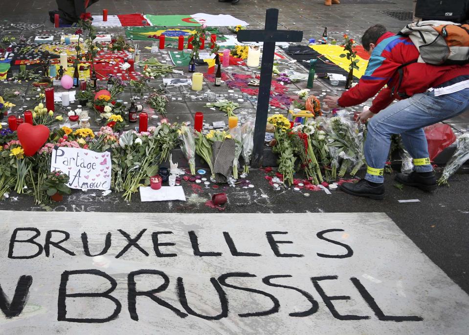 A man places flowers on a street memorial following Tuesday's bomb attacks in Brussels, Belgium, March 23, 2016. REUTERS/Francois Lenoir TPX IMAGES OF THE DAY