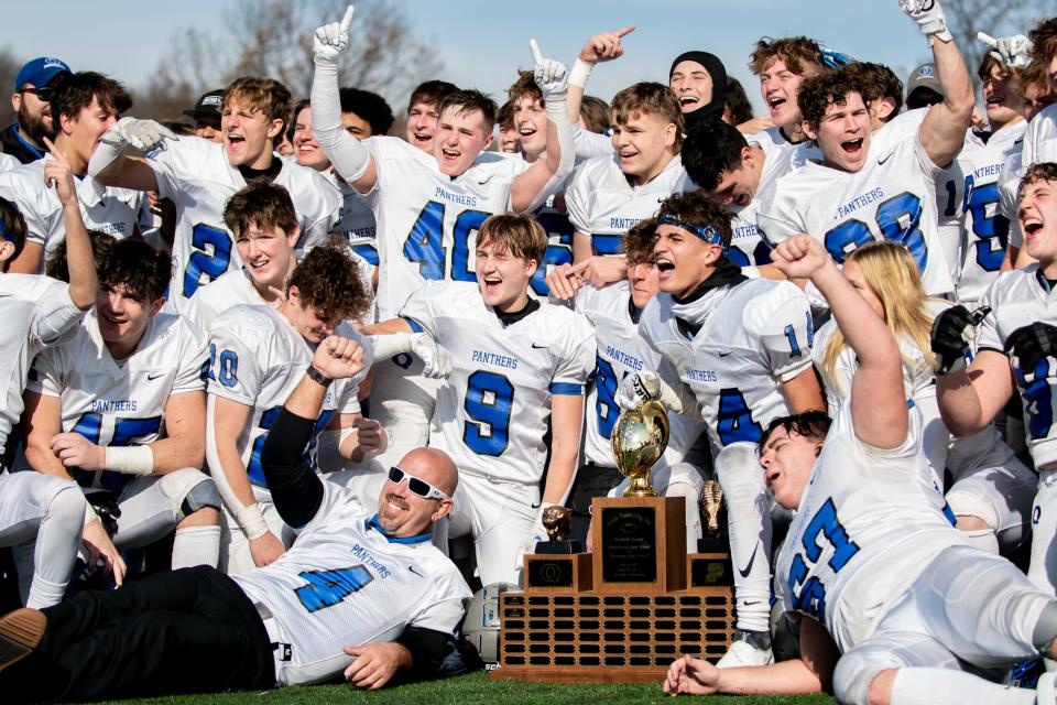 Quakertown poses around the trophy after winning the annual Thanksgiving game against Pennridge at Helman Field in Perkasie on Thursday, November 25, 2021. The Panthers shutout the Rams 21-0.