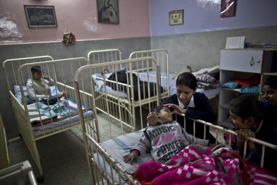 In this Sunday, Feb. 16, 2014, photo, Sonia Shawkat, 21, a Pakistani nurse, and two adult patients, right, comfort Nisha, 6, a girl, who lives at St. Joseph’s Hospice, shortly before sleeping in her bed, at the children ward of the hospice, in Rawalpindi, Pakistan. Mohammed Aqeel spent weeks at home in Pakistan waiting for death after suffering a debilitating spinal cord injury in a car crash before friends suggested he come to St. Joseph’s Hospice on the outskirts of the capital, Islamabad. Now 13 years later, his life and those of some 40 others who live on its grounds might be changed forever as this hospital of last resort faces closure over its rising debts. (AP Photo/Muhammed Muheisen)