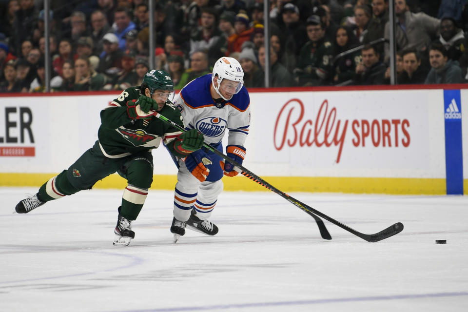 Minnesota Wild right wing Mats Zuccarello, left, and Edmonton Oilers center Zach Hyman battle for control of the puck during the second period of an NHL hockey game, Monday, Dec. 12, 2022, in St. Paul, Minn. (AP Photo/Craig Lassig)