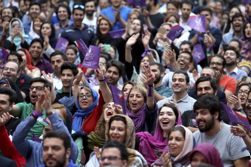 伊朗總統候選人魯哈尼的支持者，手持象徵魯哈尼的紫色旗幟。（美聯社）