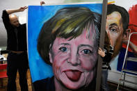 Le portrait humoristique d'Angela Merkel que l'artiste Tono Velasco tient dans la hauteur, en Espagne. (Reuters/Eloy Alonso)