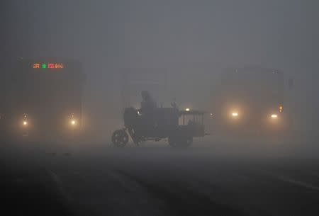 FILE PHOTO: A tricycle travels past a crossroad on a hazy day in Hefei, Anhui province March 30, 2014. REUTERS/Stringer/File Photo