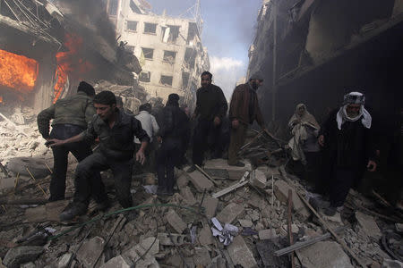 People walk on rubble as others try to put out a fire after what activists said were airstrikes followed by shelling by forces loyal to Syria's President Bashar al-Assad in the Douma neighborhood of Damascus, February 9, 2015. REUTERS/ Mohammed Badra