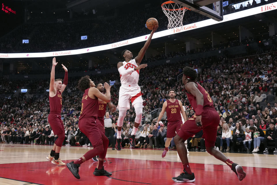 Toronto Raptors guard RJ Barrett, center, scores as Cleveland Cavaliers defenders Sam Merrill (5), Craig Porter Jr. (9), Tristan Thompson (12), Georges Niang (20) and Caris LeVert (3) defend during the first half of an NBA basketball game in Toronto, Monday, Jan. 1, 2024. (Chris Young/The Canadian Press via AP)