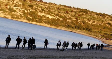 Refugees walk along a beach before trying to travel to the Greek island of Chios from the western Turkish coastal town of Cesme, in Izmir province, Turkey, in this March 5, 2016 file photo. REUTERS/Umit Bektas