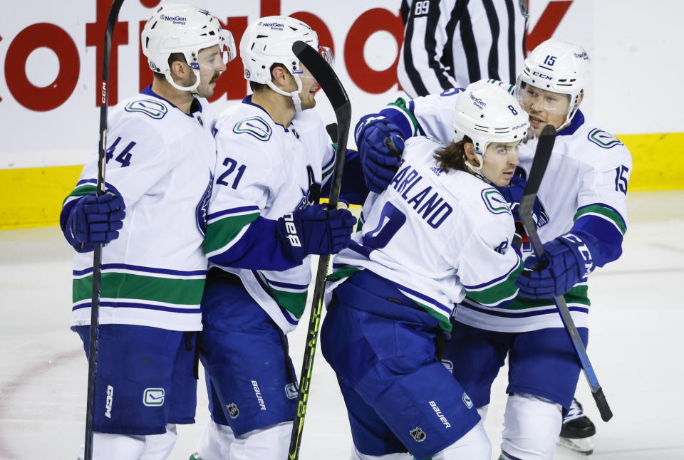 Vancouver Canucks forward Conor Garland (8) celebrates his goal with teammates during the first period of an NHL hockey game against the Calgary Flames in Calgary, Alberta on Wednesday, Dec. 14, 2022. (Jeff McIntosh/The Canadian Press via AP)