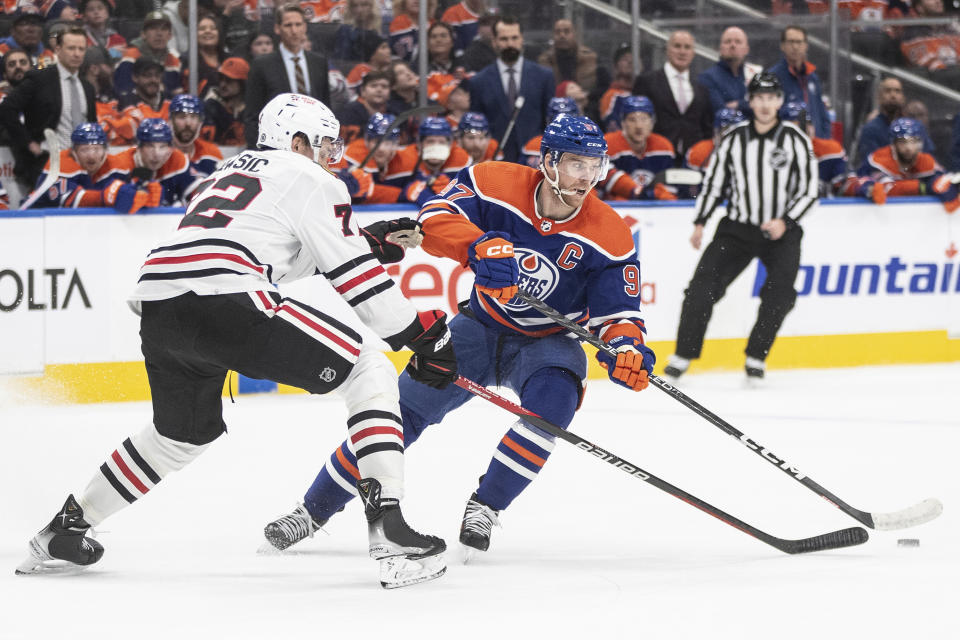 Chicago Blackhawks' Alex Vlasic, left, battles with Edmonton Oilers' Connor McDavid during the second period of an NHL hockey game in Edmonton, Alberta, on Tuesday, Dec. 12, 2023. (Jason Franson/The Canadian Press via AP)
