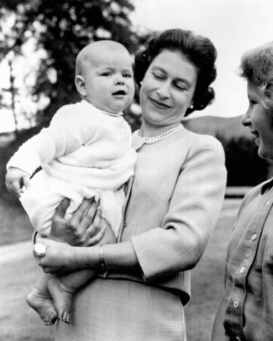 Die Königin hält ihren kleinen Prinz Andrew im November 1960 auf dem Gelände von Balmoral (PA)