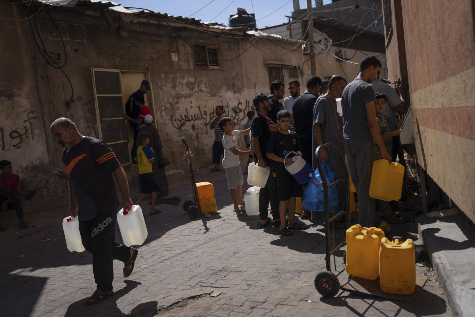 FILE - Palestinians collect water from a water tap, amid drinking water shortages, in Khan Younis, Gaza Strip, Sunday, Oct, 15, 2023. Since the Israeli military decided to cut off the Gaza Strip's water and fuel and prevent aid convoys from entering, Palestinians in Gaza have sheltered with their families far from their homes and struggled to survive. It's a grueling routine — waiting hours for bread, trying to find water, soothing children during bombings. (AP Photo/Fatima Shbair, File)