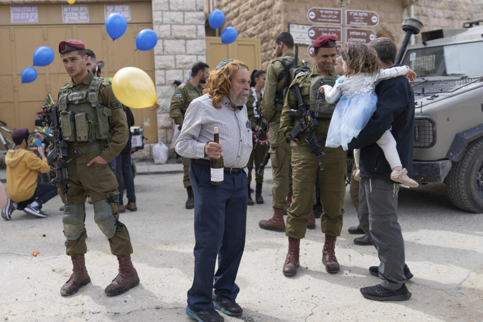 Jewish settlers dressed in costumes celebrate the Jewish holiday of Purim as soldiers secure the march in the West Bank city of Hebron, Tuesday, March 7, 2023. Hebron is a flashpoint city where several hundred hard-line Israeli settlers live in heavily guarded enclaves amid some 200,000 Palestinians. The settlers each year hold a parade on Purim – a Jewish holiday marked by costumes and revelry that commemorates the Jews' salvation from genocide in ancient Persia, as recounted in the biblical Book of Esther. (AP Photo/Ohad Zwigenberg)