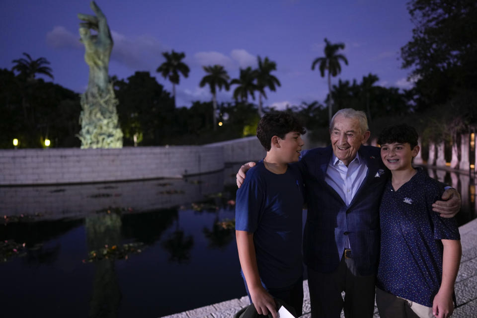 Holocaust survivor David Schaecter, 94, second right, poses for a picture with Nate Pelz, right, and Blake Kandell, two young teens he educated about the first hand experience of the Holocaust through the Young Lions of Judah program, as they greet him at an event commemorating Kristallnacht, the 1938 government-backed pogroms against Jews in Germany and Austria, at the Holocaust Memorial in Miami Beach, Fla., Sunday, Nov. 5, 2023. (AP Photo/Rebecca Blackwell)