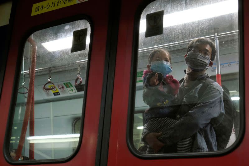 FILE PHOTO: Passengers wear face masks in a Hong Kong bound-MTR train at Lo Wu MTR station, before the closing of the Lo Wu border following the coronavirus outbreak in Hong Kong