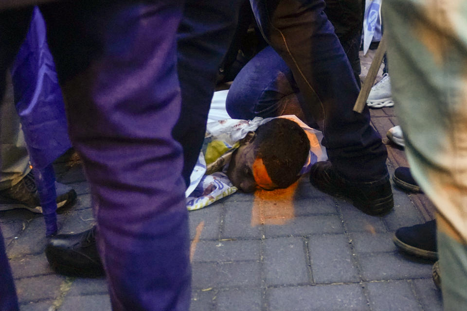 FILE - A person uses his knee to hold down an alleged suspect wounded in the assassination of presidential candidate Fernando Villavicencio, outside a school in Quito, Ecuador, Aug. 9, 2023. According to the Attorney General's Office, the captured suspect died in custody from injuries sustained in the shootout. (API via AP File)