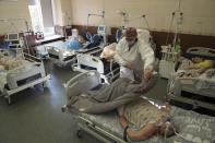 In this handout photo released by UNICEF, A nurse covers a patient with coronavirus with a blanket at the ICU at the regional hospital in Kharkiv, Ukraine, Friday, Oct. 15, 2021. Ukraine is suffering through a surge in coronavirus infections, along with other parts of Eastern Europe and Russia. While vaccines are plentiful, there is a widespread reluctance to get them in many countries — though notable exceptions include the Baltic nations, Poland, the Czech Republic, Slovenia and Hungary. (Evgeniy Maloletka, UNICEF via AP)