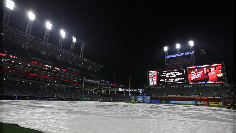 The tarp rests on the field after a baseball game between the Minnesota Twins and the Cleveland Indians is postponed due to the weather, Friday, Sept. 13, 2019, in Cleveland. The Indians and Twins will play a doubleheader on Saturday. (AP Photo/Tony Dejak)