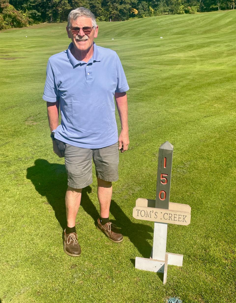 Juniper Hill general manager Dudley Darling stands next to Tom’s Creek sign that used to be planted in the wet first fairway on the Riverside Course. He brought the sign out of storage for this photo.