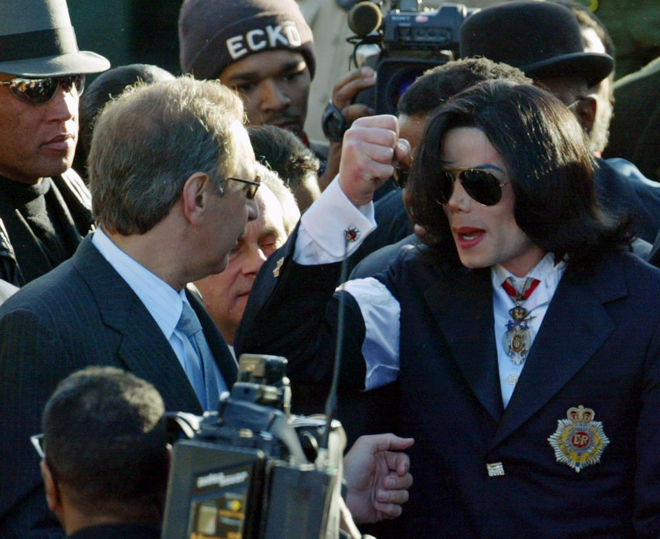 File - In this Jan. 16, 2004 file photo, Michael Jackson looks for his umbrella as he talks to his defense attorney Mark Geragos, left, as they arrive at the courthouse in Santa Maria, Calif. CNN has cut ties with Mark Geragos just hours after the celebrity attorney was named as a co-conspirator in a case accusing lawyer Michael Avenatti of trying to extort Nike. A CNN representative confirmed Monday, March 25, 2019, that Geragos is no longer a contributor to the network but didn't specify why. His name is no longer listed on CNN's website as a legal analyst. (AP Photo/Spencer Weiner, pool, file)