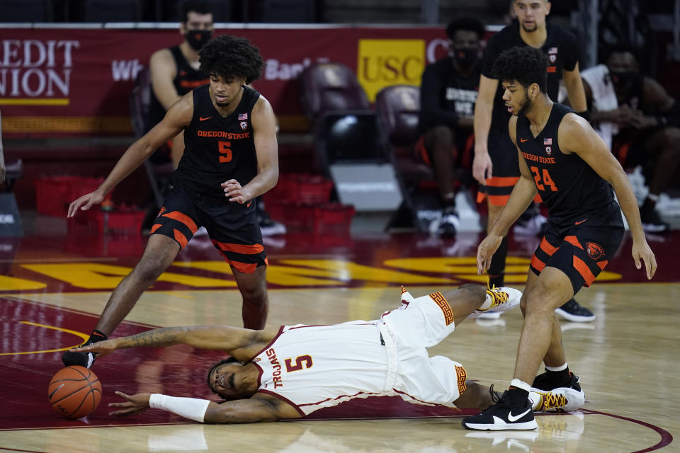 Southern California guard Isaiah White (5) reaches for the ball near Oregon State guard Ethan Thompson (5) and forward Isaiah Johnson (24) during the first half of an NCAA college basketball game Thursday, Jan. 28, 2021, in Los Angeles. (AP Photo/Ashley Landis)