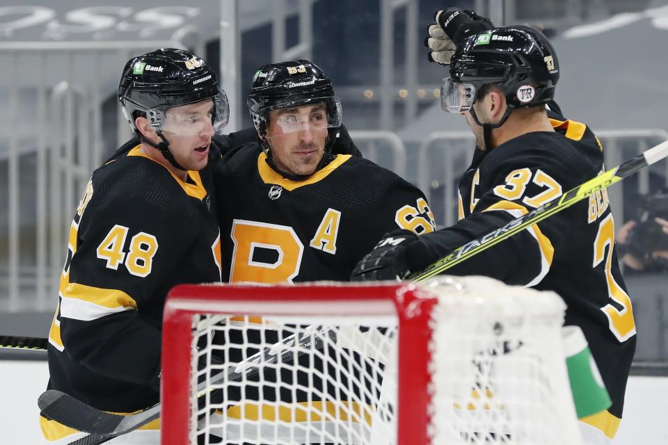 Boston Bruins' Brad Marchand (63) celebrates his goal with Matt Grzelcyk (48) and Patrice Bergeron (37) during the second period of the team's NHL hockey game against the Washington Capitals, Friday, March 5, 2021, in Boston. (AP Photo/Michael Dwyer)