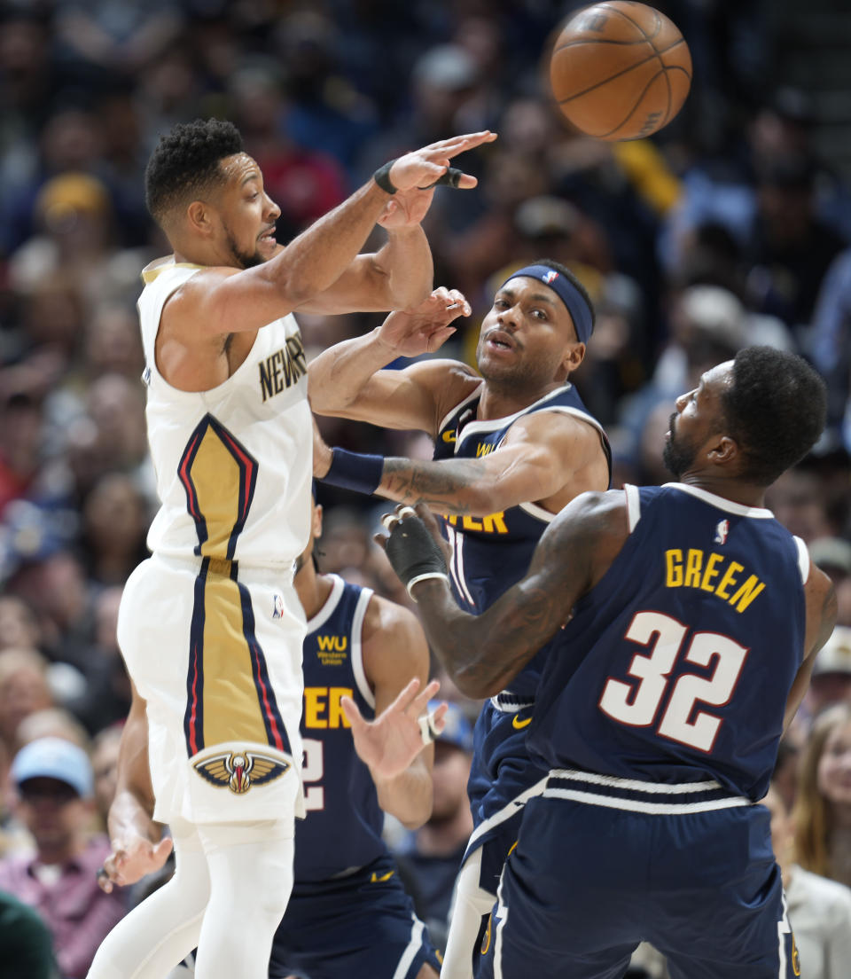 New Orleans Pelicans guard CJ McCollum, left, passes the ball as Denver Nuggets forwards Jeff Green, front right, and Bruce Brown defend in the first half of an NBA basketball game Tuesday, Jan. 31, 2023, in Denver. (AP Photo/David Zalubowski)