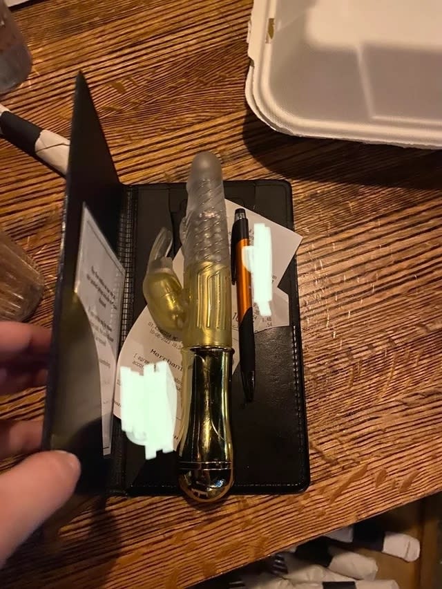 A waiter's organizer with receipts, a pen, and a sex toy