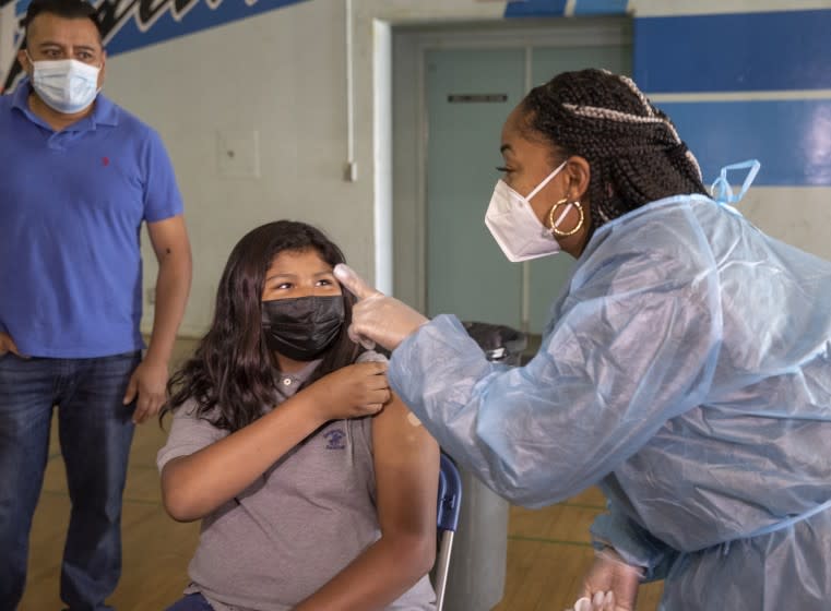 SAN FERNANDO, CA - AUGUST 30, 2021:Lynn-Ti Allen, right, a licensed vocational nurse, points out the area to sit and be monitored for any side effects after giving the first dose of the Pfizer vaccine to Katherine Baltazar,12, a 7th grader at San Fernando Middle School in San Fernando. A mobile COVID-19 vaccine clinic was set up inside the gymnasium at San Fernando Middle School to inoculate LAUSD employees and students age 12 and older. (Mel Melcon / Los Angeles Times)