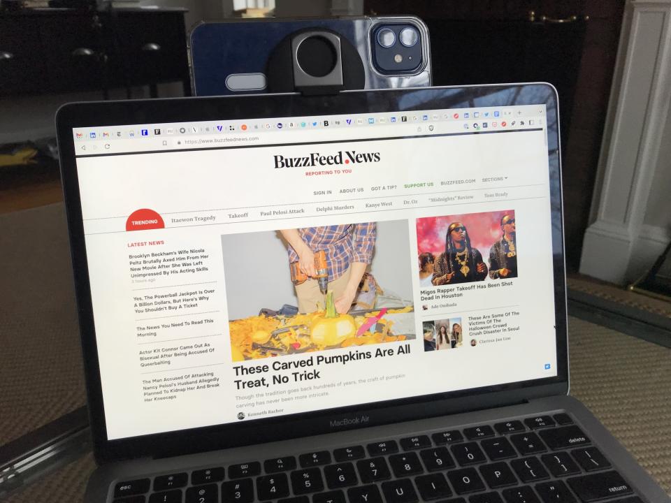 A phone attached to the author's laptop with the BuzzFeed News homepage and about forty tabs opened