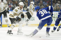 Boston Bruins right wing David Pastrnak (88) slides the puck past Tampa Bay Lightning left wing Brandon Hagel (38) during the first period of an NHL hockey game Wednesday, March 27, 2024, in Tampa, Fla. (AP Photo/Chris O'Meara)