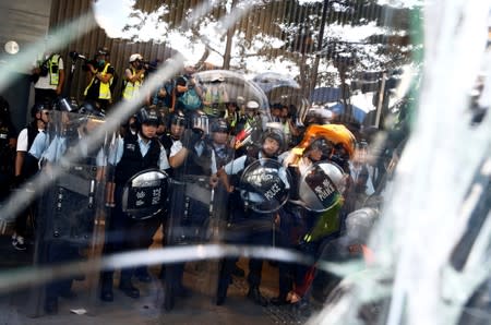 Riot police stand behind glass smashed by anti-extradition bill protesters at the Legislative Council building during the anniversary of Hong Kong's handover to China in Hong Kong