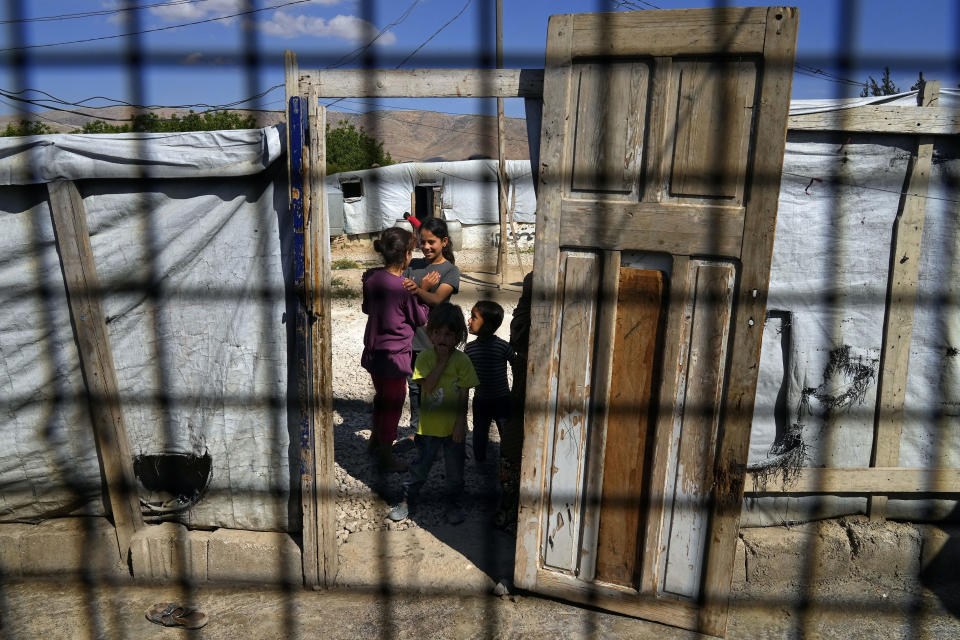 Syrian children, seen through a tent window, stand at a refugee camp in the town of Bar Elias, in Lebanon's Bekaa Valley, Tuesday, June 13, 2023. Aid agencies are yet again struggling to draw the world's attention back to Syria in a two-day donor conference hosted by the European Union in Brussels for humanitarian aid to Syrians that begins Wednesday. Funding from the conference also goes toward providing aid to some 5.7 million Syrian refugees living in neighboring countries, particularly Turkey, Lebanon and Jordan. (AP Photo/Bilal Hussein)