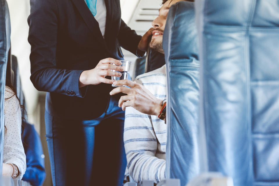 Air stewardess serving water inside an airplane, close up of hands, unrecognizable person.