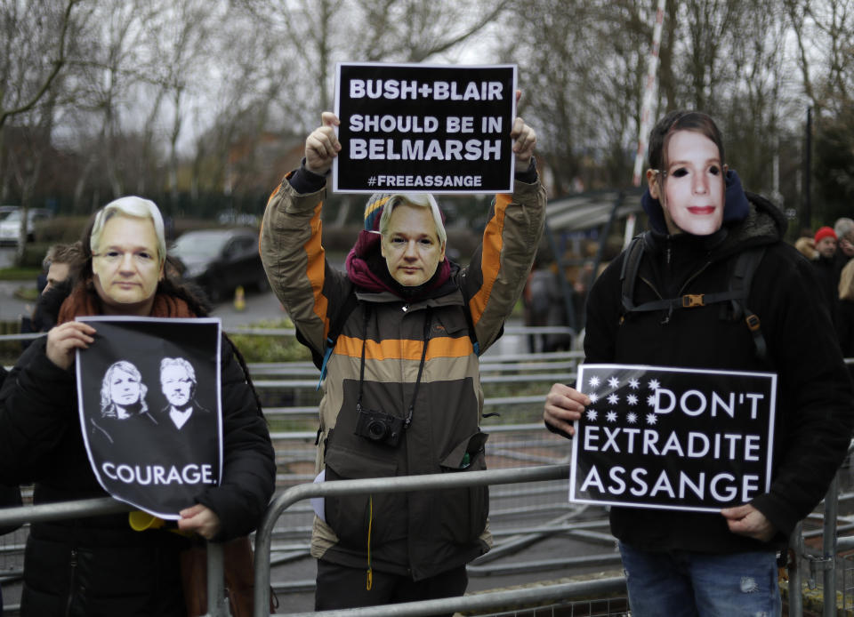 A supporter wears a mask depicting Julian Assange, center, and holds a sign which reads 'Bush and Blair should be in Belmarsh' as he protests with others against the extradition of Wikileaks founder Julian Assange outside Belmarsh Magistrates Court in London, Monday, Feb. 24, 2020. The U.S. government and WikiLeaks founder Julian Assange will face off Monday in a high-security London courthouse, a decade after WikiLeaks infuriated American officials by publishing a trove of classified military documents. (AP Photo/Matt Dunham)