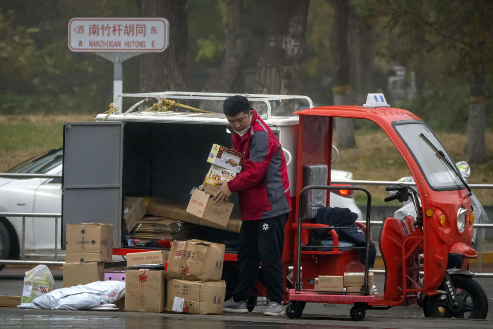 A delivery courier sorts packages along a street in Beijing, Friday, Nov. 11, 2022. China's biggest online shopping festival, known as Singles' Day, is typically an extravagant affair as Chinese e-commerce firms like Alibaba and JD.com ramp up marketing campaigns and engage top livestreamers to hawk everything from lipstick to furniture as they race to break sales records of previous years. (AP Photo/Mark Schiefelbein)