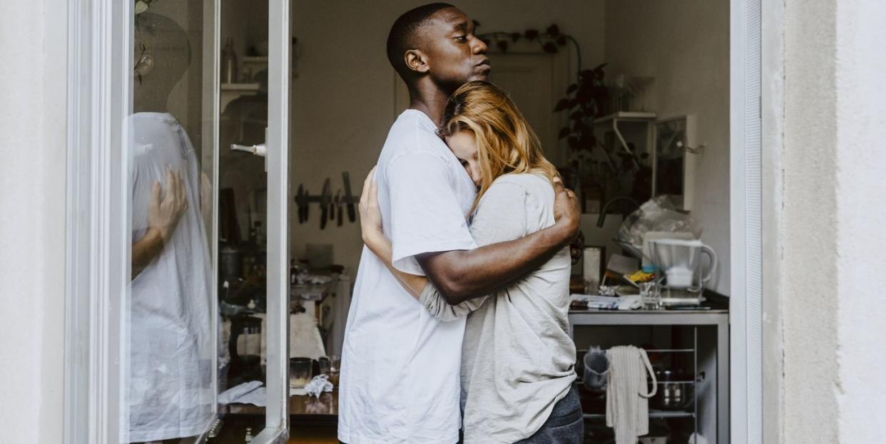 son consoling depressed mother seen through window at home