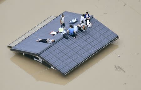 An aerial view shows local residents seen on the roof of submerged house at a flooded area as they wait for a rescue in Kurashiki, southern Japan, in this photo taken by Kyodo July 7, 2018. Mandatory credit Kyodo/via REUTERS