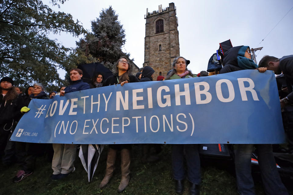 A group holds a sign at the intersection of Murray Ave. and Forbes Ave. in the Squirrel Hill section of Pittsburgh, during a memorial vigil for the victims of the shooting at the Tree of Life Synagogue where a shooter opened fire, killing multiple people and wounding others, including several police officers, Saturday, Oct. 27, 2018. (AP Photo/Gene J. Puskar)